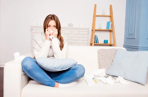 Sick  girl with fever sneezing in tissue sitting on sofa, close — Stock Photo, Image