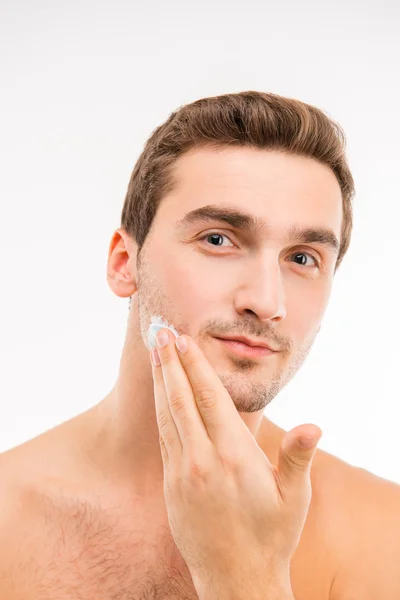 Молодой красивый мужчина со сливками для бритья на щеке — стоковое фото