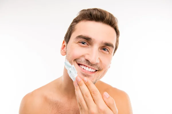 Bonito jovem esfregando espuma de barbear em seu queixo — Fotografia de Stock