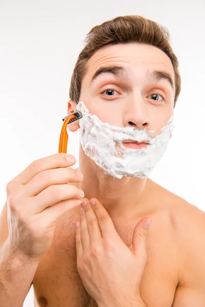 Красивый смешной мужчина с пеной для бритья на лице и бритвой — стоковое фото
