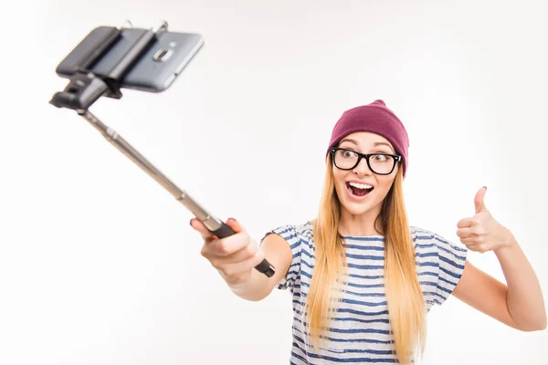Chica feliz en la tapa y gafas haciendo foto por palo selfie y t —  Fotos de Stock