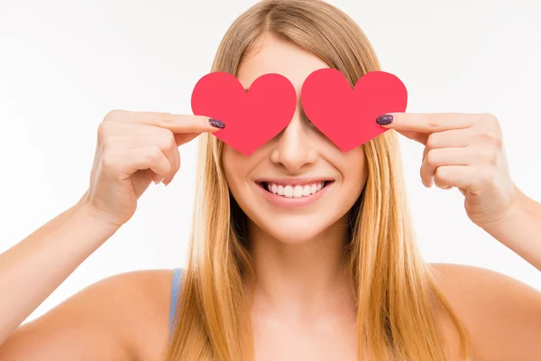 Jovem alegre escondendo os olhos atrás de dois corações de papel, cl Fotografia De Stock