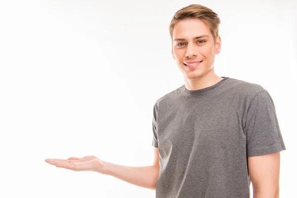 Joven sonriente en camiseta gris ofreciendo un producto — Foto de Stock