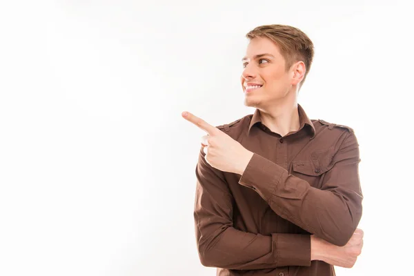 Pretty  young smiling man in brown shirt gesturing and pointing — Stock Photo, Image