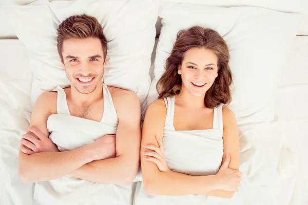 美丽的夫妇在爱躺在床上，横过手中 — 图库照片