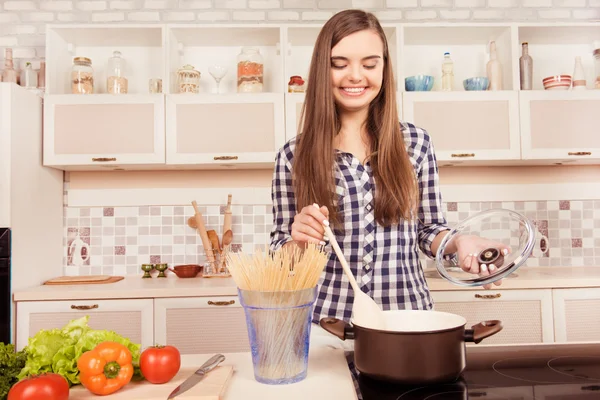 Gelukkig jonge vrouw kokend spaghetti in de keuken — Stockfoto