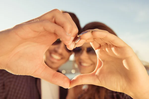 Happy romantic couple in love gesturing a heart with fingers