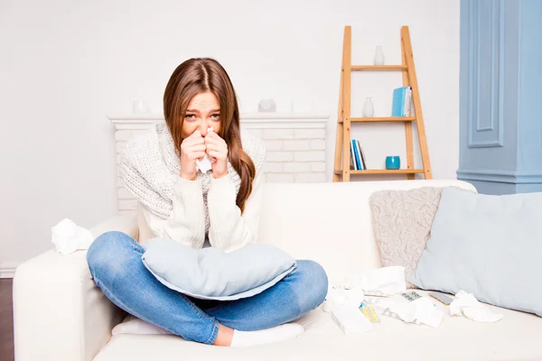 Sick  girl with fever sneezing in tissue sitting on sofa, close — Stock Photo, Image