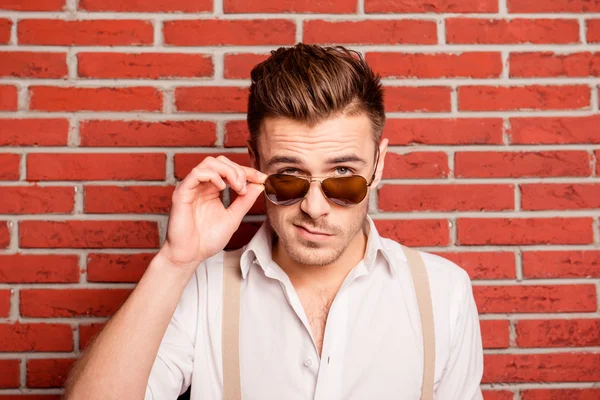 Serious young man with grimace on face touching his spectacles — Stock Photo, Image