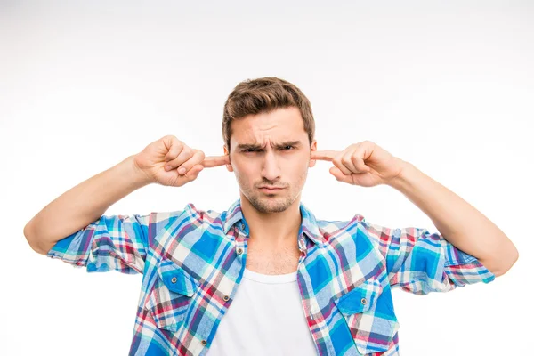 Carino giovane uomo chiudendo le orecchie e accigliandosi — Foto Stock