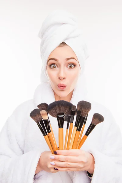Забавная женщина с кисточками для макияжа с полотенцем на голове — стоковое фото