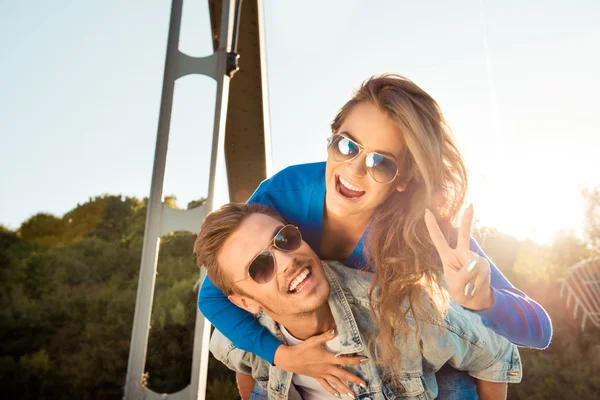 Pozytywny śmieszne para zakochanych na moście gestykulacji dwoma palcami — Zdjęcie stockowe