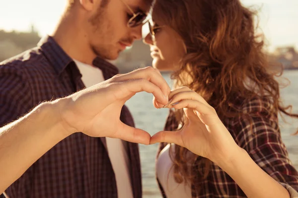 Romántica tierna pareja enamorada gesticulando un corazón con los dedos ne —  Fotos de Stock