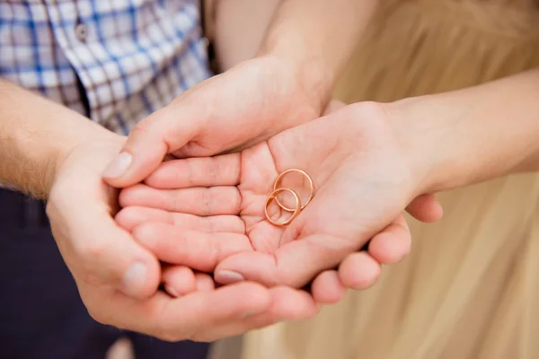 Closeup photo of a happy couple in love holding wedding rings — Stock Photo, Image