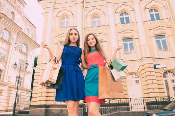 Twee jonge vrouwen met boodschappentassen wandelen in de stad — Stockfoto