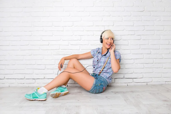 Happy girl sitting on the floor and listening to music on headph — Stock Photo, Image