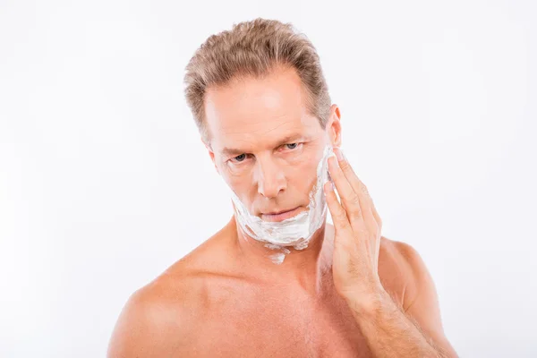 Aged handsome man smearing shaving foam on his chin — Stock Photo, Image