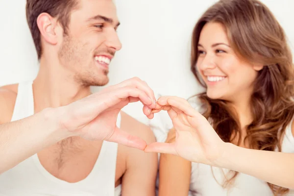 Feliz hombre y mujer encantador gesto de un corazón con los dedos —  Fotos de Stock