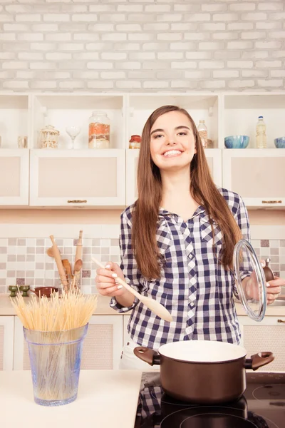 Mooie jonge meisje kokend spaghetti in de keuken — Stockfoto