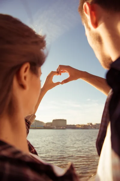 Sweet couple in love gesturing a heart with fingers on the sky — Stock Photo, Image