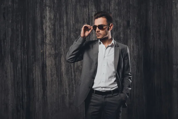 Hombre guapo y descarado con gafas cogidas de la mano en un bolsillo en el — Foto de Stock