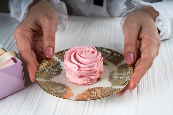 Pembe şekerlemeli kadın elleri ve çay tabağı.