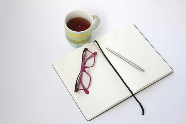 Boş açık defter fincan çay ve kalem ile