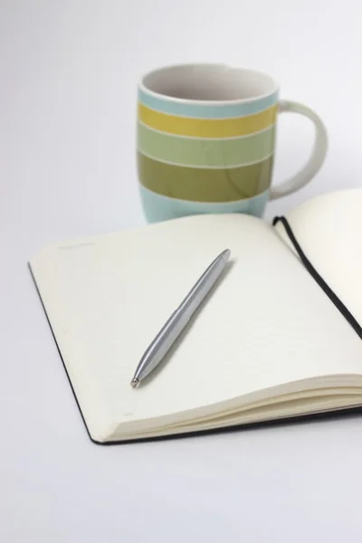 Boş açık defter fincan çay ve kalem ile