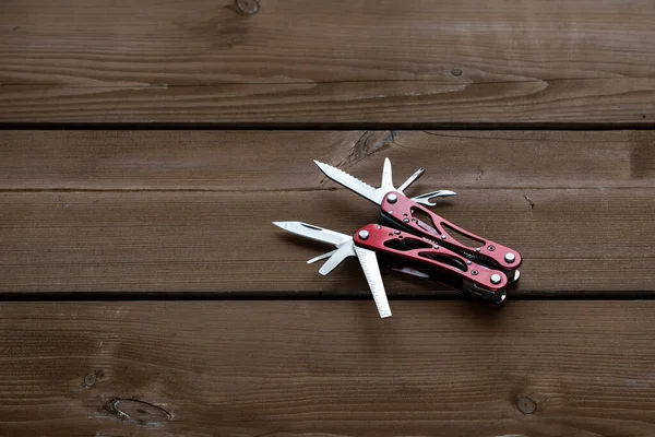 Çoklu işlevsel cep çakısı bir keseyi ahşap bir masaya yerleştirilir.