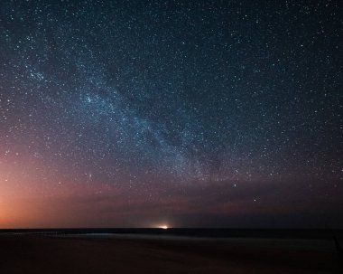 Gece gökyüzü deniz kenarında Samanyolu görünür