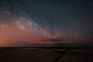 Gece gökyüzü deniz kenarında Samanyolu görünür