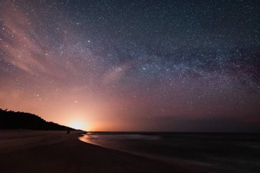 Gece gökyüzü deniz kenarında Samanyolu görünür
