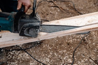 Bir işçi elektrikli testereyle tahtayı keser.