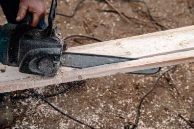 Bir işçi elektrikli testereyle tahtayı keser.