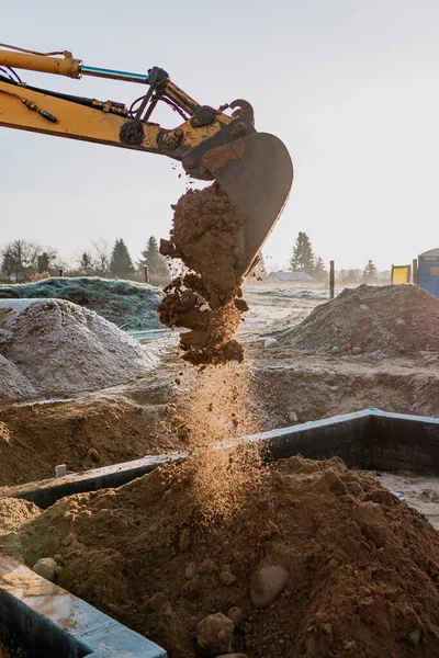 backfilling of foundations by an excavator at the construction site of a single-family house