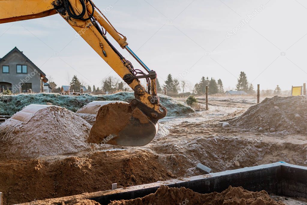 backfilling of foundations by an excavator at the construction site of a single-family house