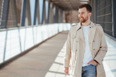 Sokakta bej ceketli bir adam yürüyor.