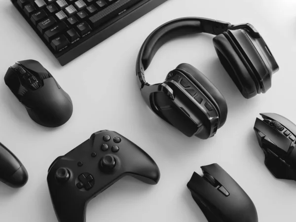 Oyun teçhizatı, fare, klavye, joystick, beyaz masa arka planında kulaklık içeren oyun alanı kavramı.