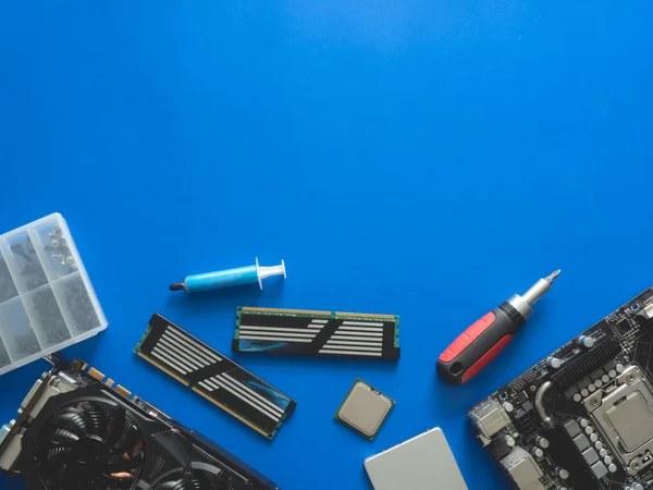 Sabit disk, ram, işlemci, grafik kartı ve anakart içeren bilgisayar parçalarının üst görünümü mavi tablo arka planında.