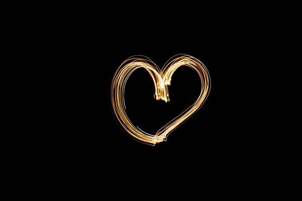 ライトペイントハート形 ブラックを背景にゴールドライトでハートを描きました 長時間露光写真 2月14日バレンタインデーの背景写真 — ストック写真