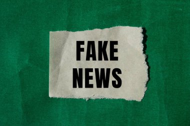 Fake news message written on ripped torn paper background. Conceptual Fake news symbol. Copy space.