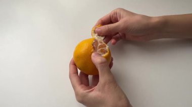 Bir el, beyaz bir masada mandalinayı soyar.