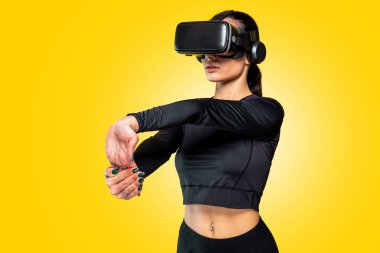 Güzel, beyaz tenli spor sporcusu kadın antrenmanı, jimnastik yaparken ince esmer pozlar veren bir stüdyo çekimi, ileri teknoloji VR gözlükleri takarak esneme hareketleri.