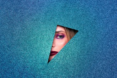 Güzel, çekici, sarışın, açık mavi gözlü, ön planda mavi parıltılı poz veren genç bir kadın, kameraya bakan seksi bir kızın stüdyo fotoğrafçılığı.