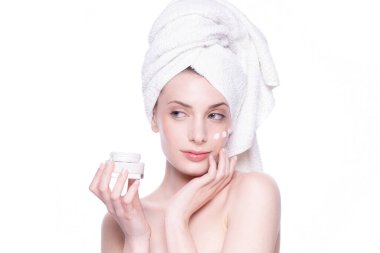 Temiz, yumuşak tenli, beyaz arka planda krem süren güzel, çekici, sarışın genç bir kadın. Güzellik bakımı yüz bakımı. Doğal stüdyo sağlıklı kozmetik portre. Kozmetik, güzellik, kaplıca.