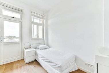 Pencerenin yanındaki yatak ve komodinin yanında.