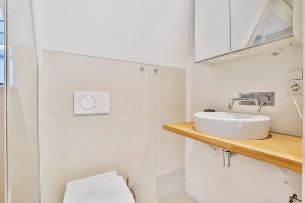 Простой дизайн ванной комнаты с туалетом и деревянным столиком — стоковое фото