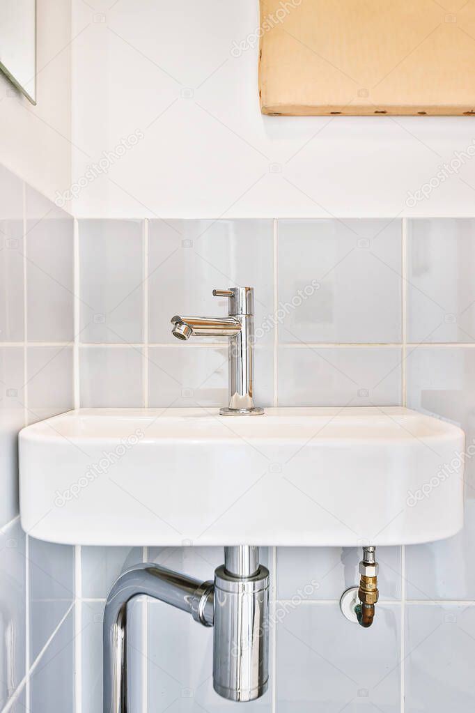 Sink with tap on tiled wall