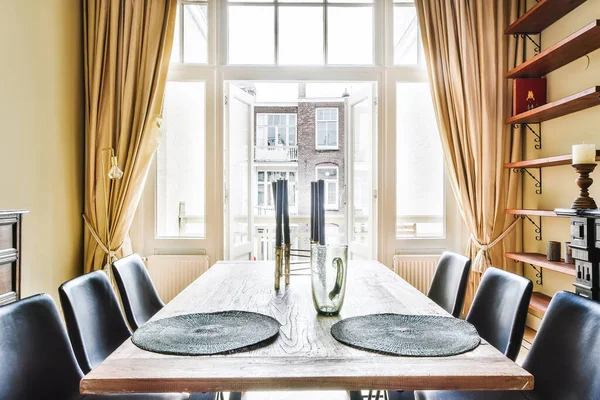 Mesa de jantar contra janela com cortinas — Fotografia de Stock