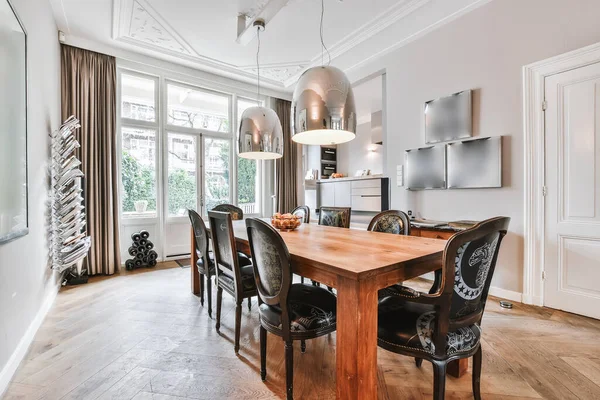 Dining table with pendant lamps against kitchen